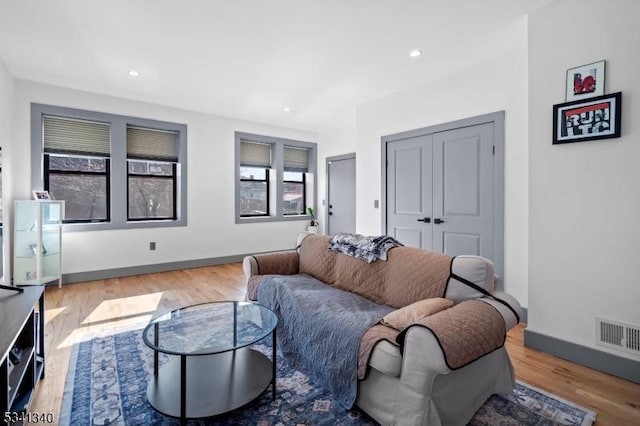 living area featuring baseboards, visible vents, wood finished floors, and recessed lighting