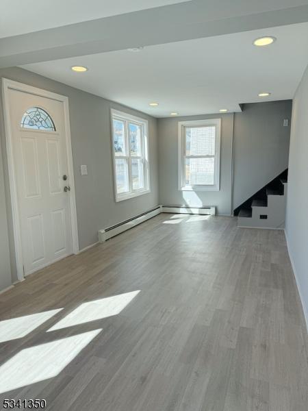 foyer featuring stairs, baseboard heating, wood finished floors, and recessed lighting