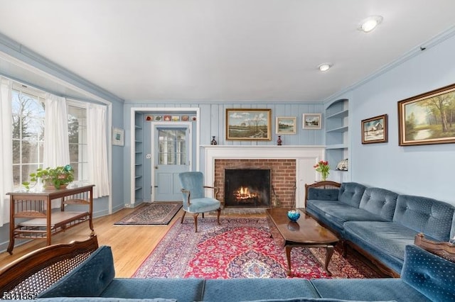 living room with a fireplace, built in features, wood finished floors, and ornamental molding