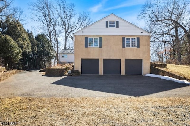 view of property exterior featuring stucco siding, driveway, and an attached garage