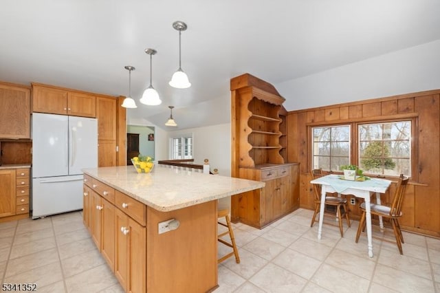 kitchen with a kitchen island, vaulted ceiling, light stone counters, freestanding refrigerator, and open shelves