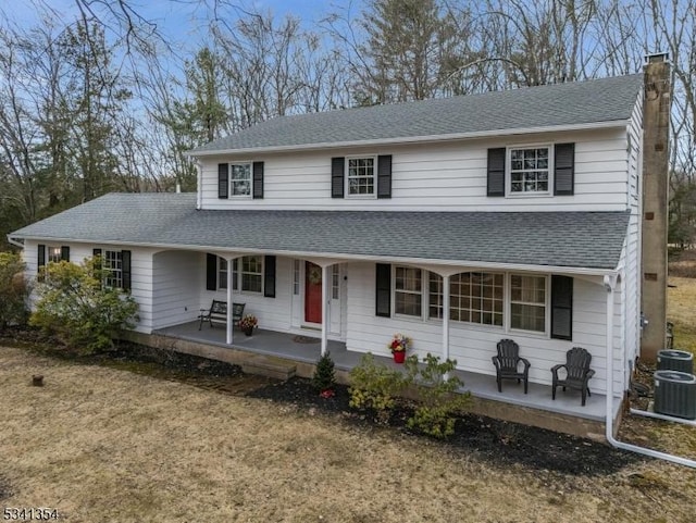 view of front of home featuring a shingled roof, covered porch, a chimney, and central air condition unit