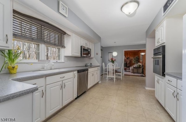 kitchen with stainless steel appliances, a sink, and white cabinetry