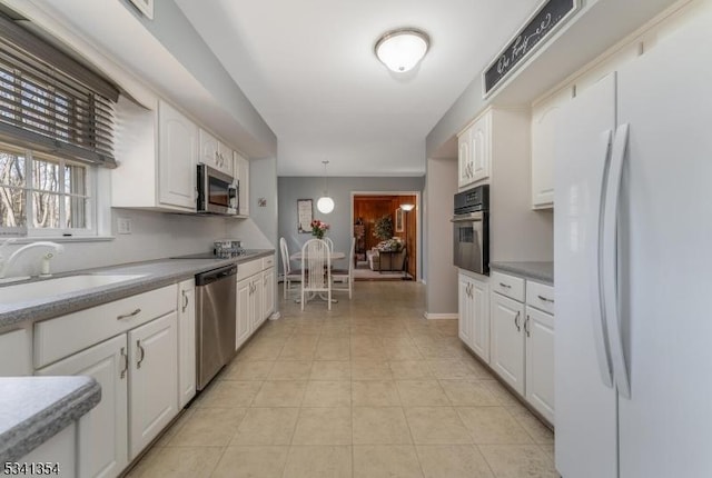 kitchen with white cabinets, light tile patterned floors, stainless steel appliances, and a sink