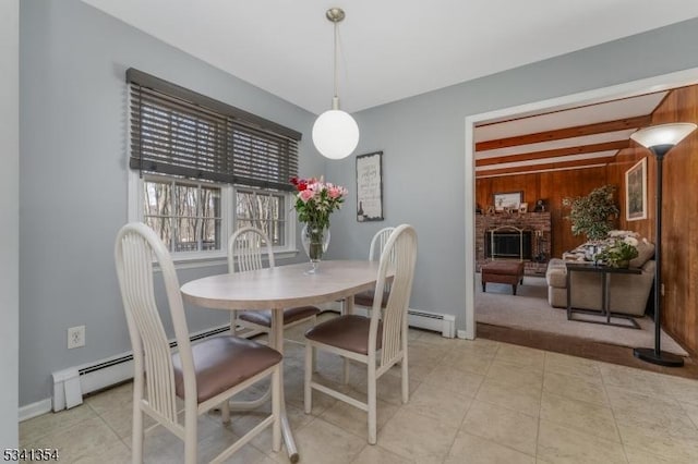 dining area with a fireplace, wooden walls, baseboard heating, and light tile patterned floors