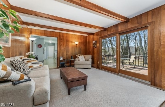 carpeted living room featuring wood walls and beamed ceiling