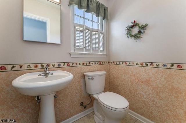 half bathroom featuring wainscoting, toilet, and baseboards