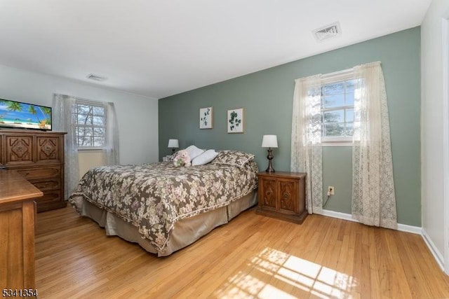 bedroom with light wood-style floors, visible vents, and baseboards