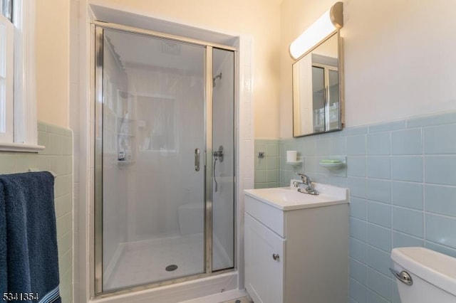 full bathroom with tile walls, toilet, wainscoting, a shower stall, and vanity