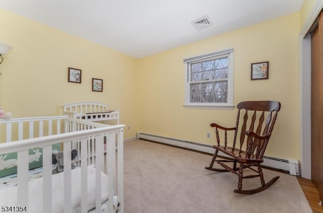 bedroom featuring a baseboard heating unit, visible vents, and carpet flooring