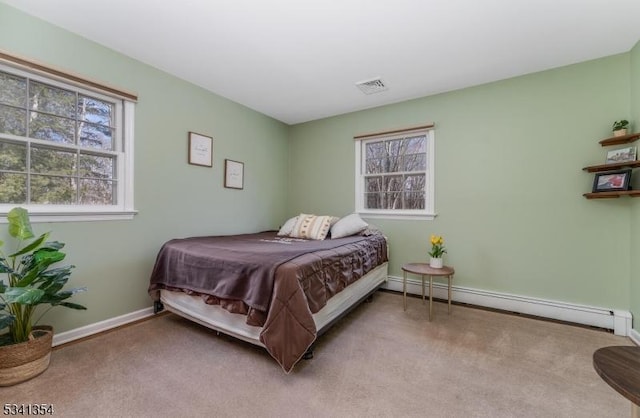 carpeted bedroom featuring visible vents, a baseboard heating unit, and baseboards