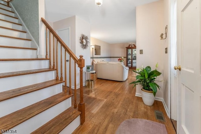 foyer entrance featuring stairs, wood finished floors, visible vents, and baseboards