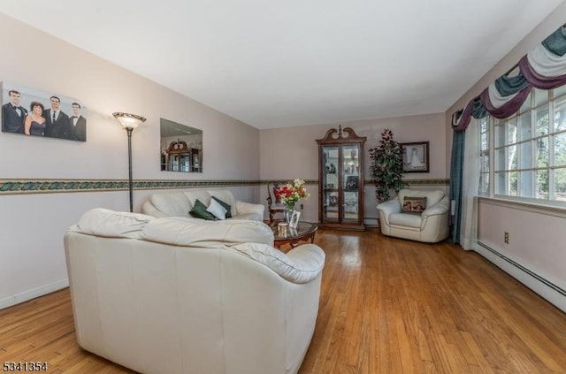 living room with a baseboard heating unit, light wood-type flooring, and baseboards