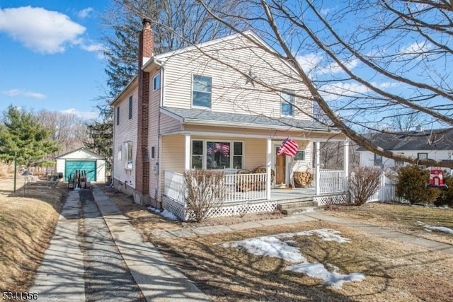 view of front of property featuring a chimney, a porch, concrete driveway, and an outbuilding