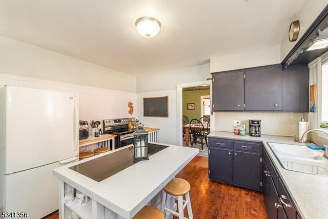 kitchen featuring dark wood-style floors, freestanding refrigerator, light countertops, open shelves, and a sink