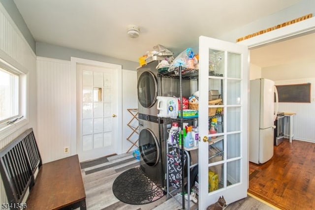 washroom featuring stacked washer and dryer, laundry area, and wood finished floors