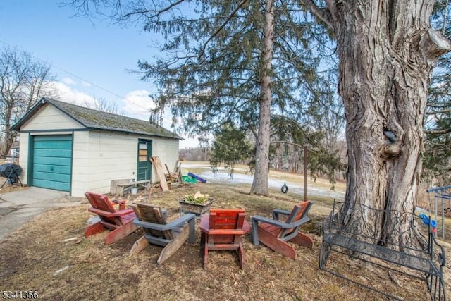 view of yard featuring a detached garage, aphalt driveway, and an outdoor structure