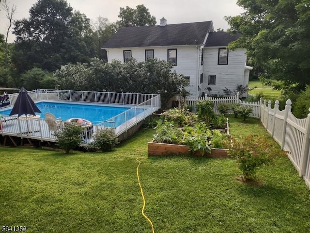 view of swimming pool with a lawn, a vegetable garden, a fenced in pool, and a fenced backyard