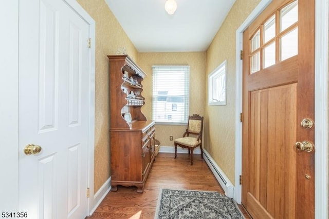 doorway featuring a baseboard heating unit, wallpapered walls, baseboards, and light wood-style floors