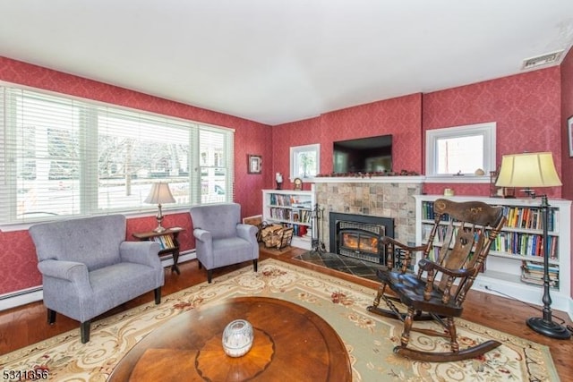 living room with baseboard heating, a fireplace, wood finished floors, and wallpapered walls