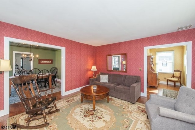 living area featuring a chandelier, wood finished floors, and wallpapered walls