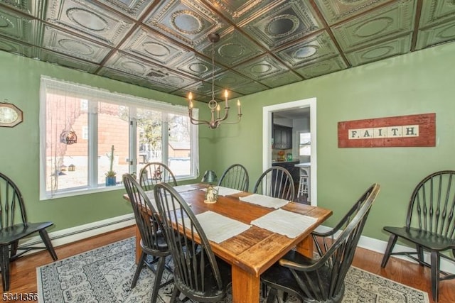 dining space with dark wood-style flooring, a baseboard radiator, an ornate ceiling, and baseboards