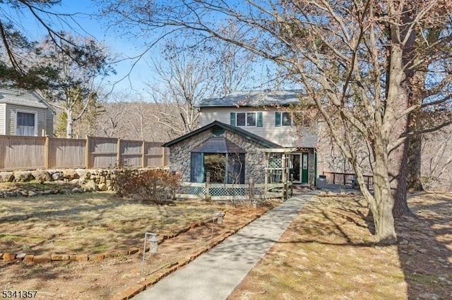 view of front of property featuring stone siding and fence