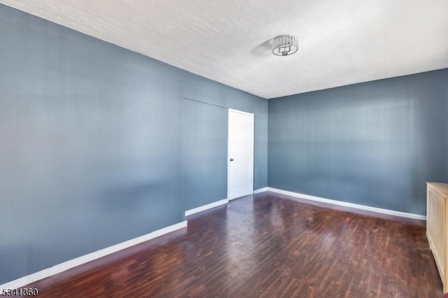 empty room with a textured ceiling, baseboards, and wood finished floors