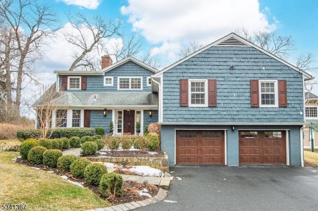 view of front of house with aphalt driveway, a chimney, and an attached garage