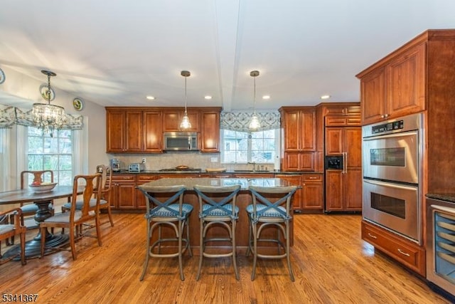 kitchen with appliances with stainless steel finishes, wine cooler, a wealth of natural light, and wood finished floors