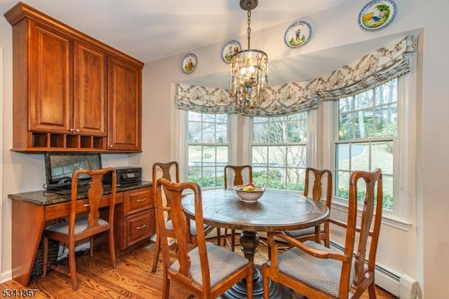 dining area with a baseboard heating unit, built in desk, light wood-style flooring, and an inviting chandelier