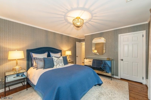 bedroom featuring wood finished floors, crown molding, and wallpapered walls