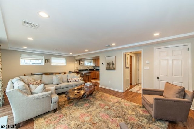 living room featuring recessed lighting, wood finished floors, visible vents, and a healthy amount of sunlight