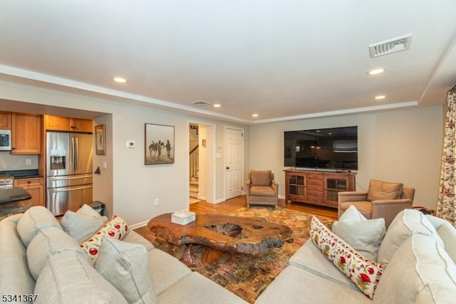 living area with light wood-style flooring, recessed lighting, visible vents, and stairway