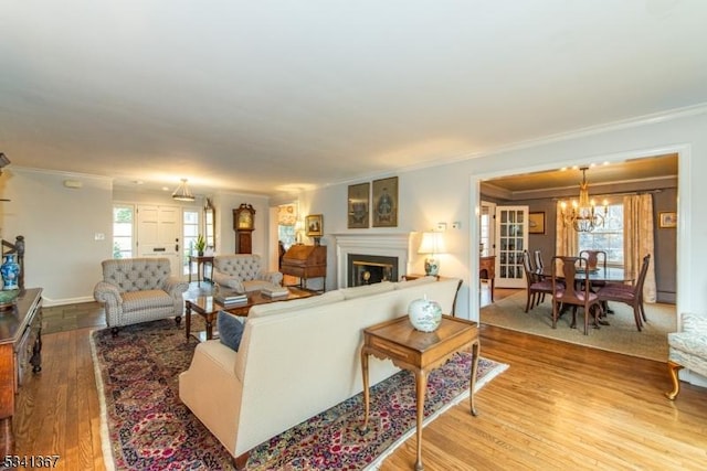 living area featuring a fireplace, wood finished floors, a wealth of natural light, and crown molding