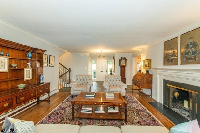 living area featuring wood finished floors, stairway, a fireplace with flush hearth, and crown molding