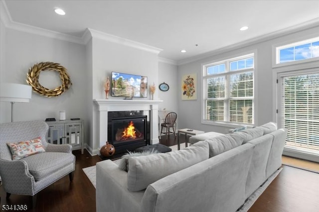 living room with dark wood-style floors, recessed lighting, crown molding, and a glass covered fireplace