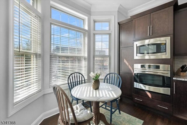 dining area with dark wood-style flooring, crown molding, and baseboards