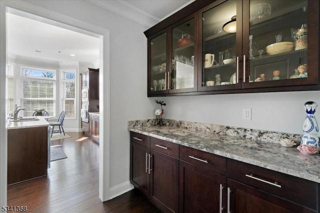 bar featuring ornamental molding, a sink, dark wood finished floors, and baseboards