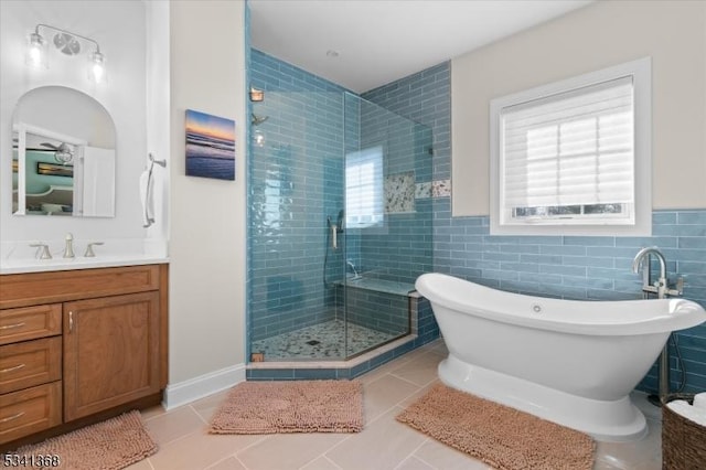 bathroom featuring a stall shower, tile patterned flooring, a freestanding tub, and vanity