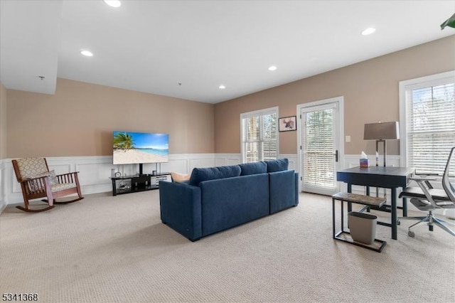 carpeted living area with a wainscoted wall, recessed lighting, and a healthy amount of sunlight