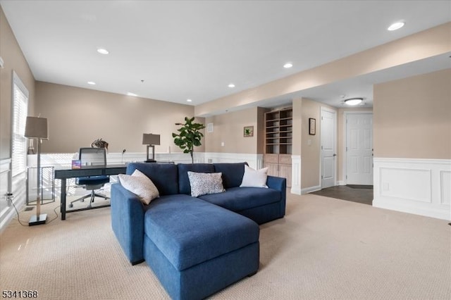 carpeted living area with recessed lighting, a wainscoted wall, and a decorative wall