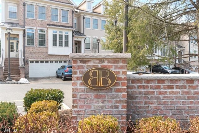 community sign with a garage and concrete driveway