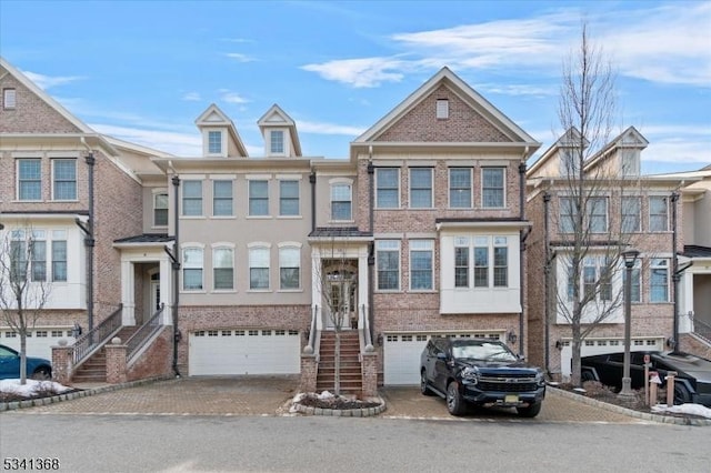 multi unit property with driveway, a garage, and brick siding