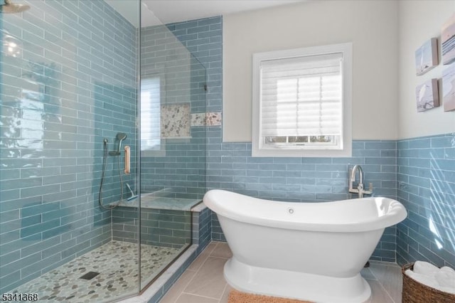 full bath with a freestanding tub, a wainscoted wall, tile walls, a shower stall, and tile patterned floors