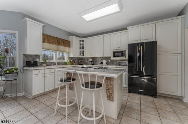 kitchen featuring gas cooktop, light countertops, backsplash, freestanding refrigerator, and built in microwave