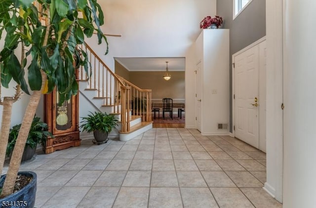 entryway with visible vents, baseboards, a towering ceiling, stairway, and light tile patterned flooring