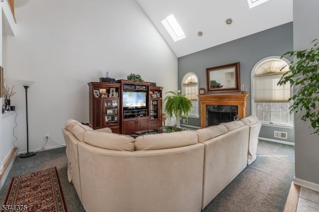 carpeted living area featuring a skylight, baseboards, visible vents, high vaulted ceiling, and a high end fireplace