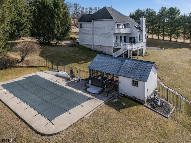 rear view of house featuring fence private yard, metal roof, a balcony, and an outdoor structure