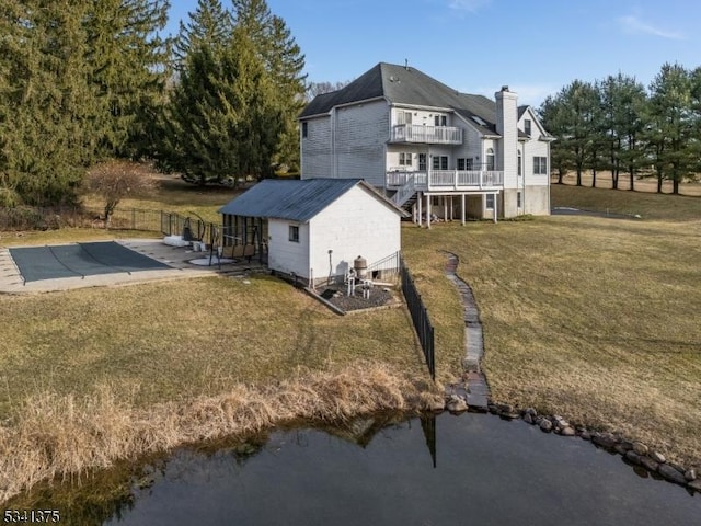 back of house with a fenced in pool, a lawn, a balcony, a chimney, and fence